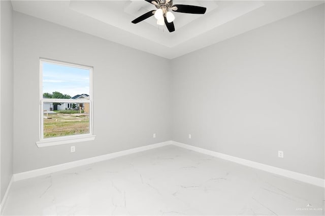 spare room featuring a raised ceiling and ceiling fan