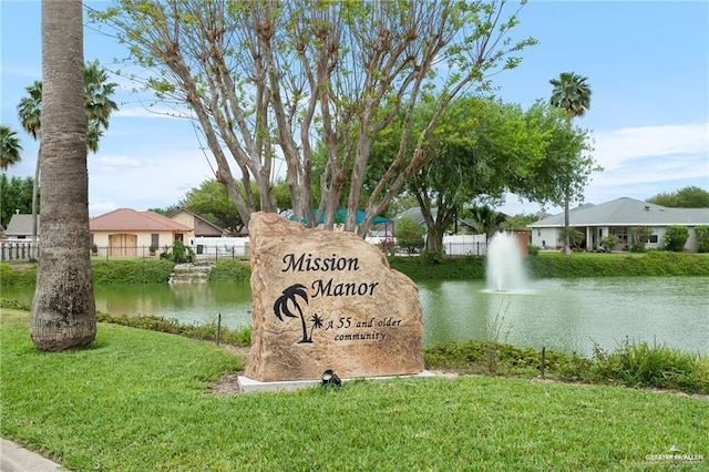 community sign featuring a yard and a water view