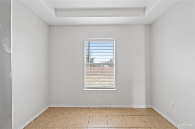 tiled spare room featuring a tray ceiling and plenty of natural light