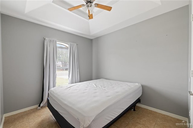 tiled bedroom with ceiling fan and a tray ceiling