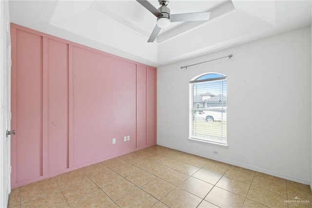 tiled spare room with a raised ceiling and ceiling fan