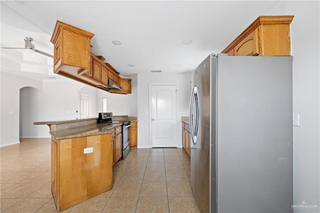 kitchen with kitchen peninsula, appliances with stainless steel finishes, dark stone counters, and light tile patterned flooring