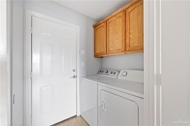 clothes washing area with washer and dryer, cabinets, and light tile patterned floors