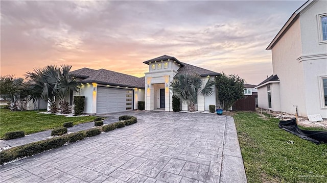 view of front of home with an attached garage, fence, decorative driveway, stucco siding, and a front yard