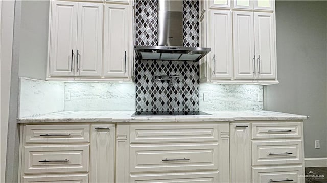 kitchen with wall chimney exhaust hood, white cabinetry, light stone counters, and backsplash