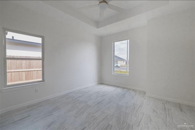 spare room with a raised ceiling and ceiling fan