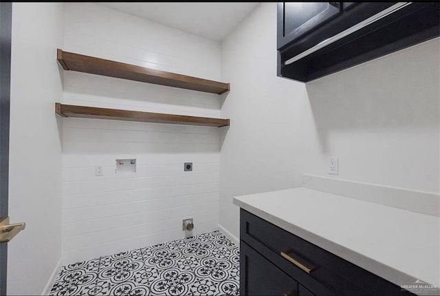 laundry room with hookup for an electric dryer, light tile patterned floors, and cabinets