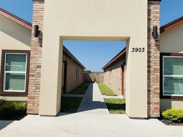 view of side of property with a patio area, fence, and stucco siding