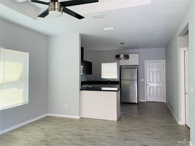 kitchen with baseboards, visible vents, dark countertops, wood finished floors, and freestanding refrigerator