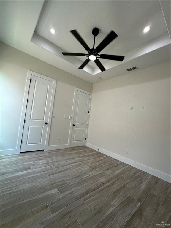 unfurnished room featuring ceiling fan, a raised ceiling, and wood-type flooring