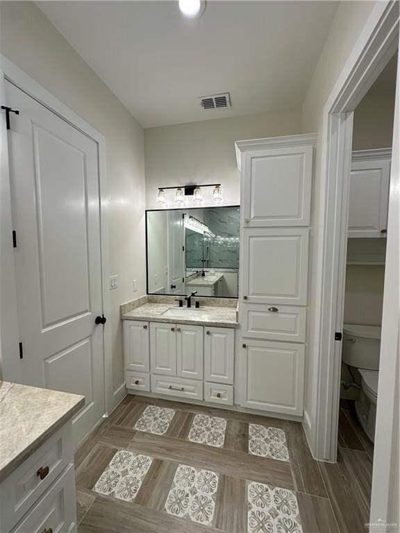 bathroom with hardwood / wood-style floors, vanity, and toilet