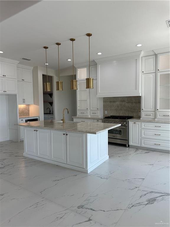 kitchen with high end range, a center island with sink, white cabinetry, and hanging light fixtures