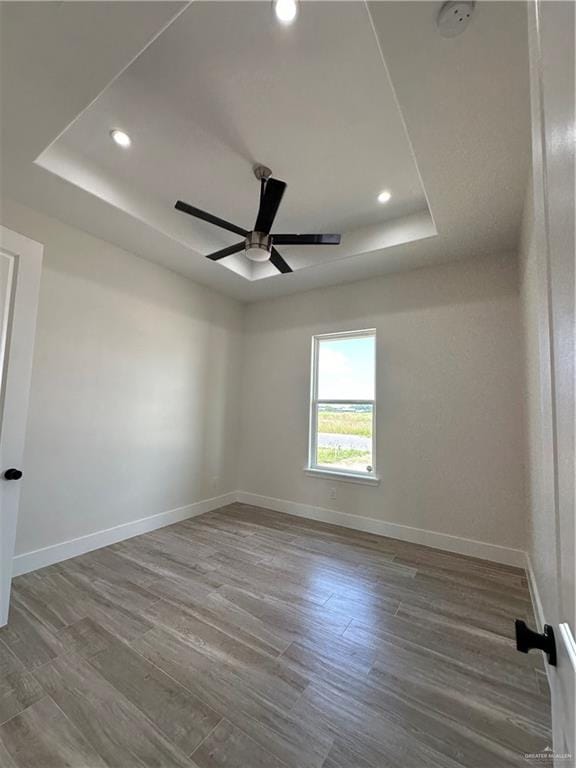 spare room featuring hardwood / wood-style floors, a raised ceiling, and ceiling fan