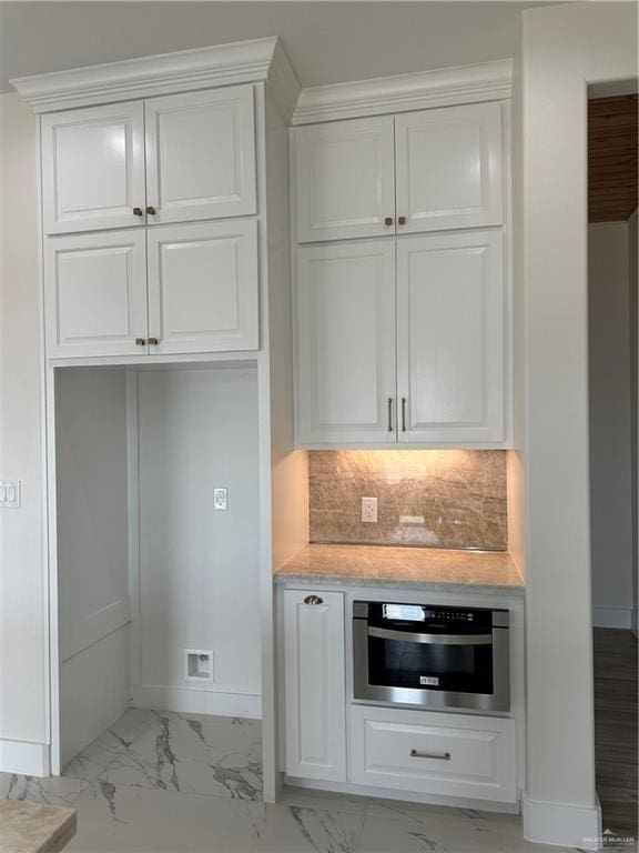 bar featuring oven, light stone countertops, white cabinetry, and backsplash