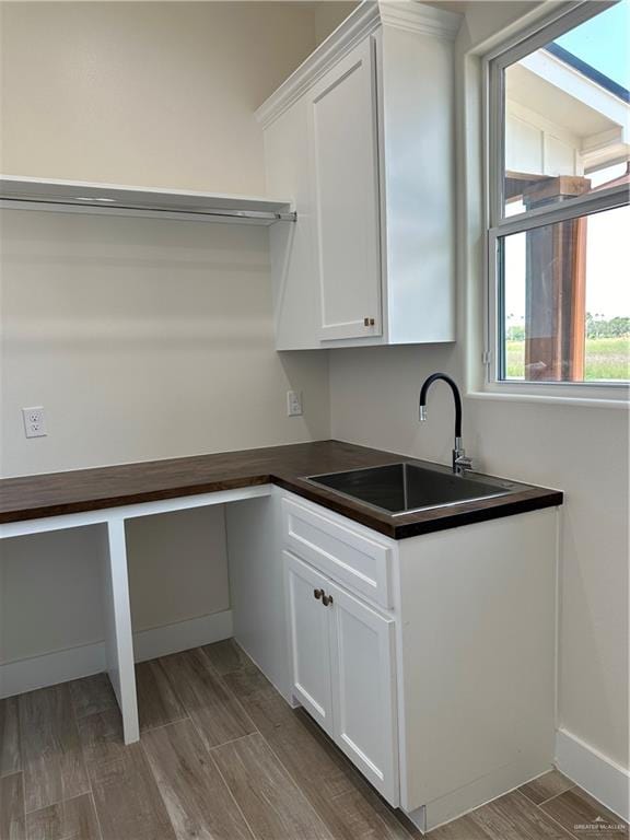 kitchen with white cabinets, hardwood / wood-style floors, and sink