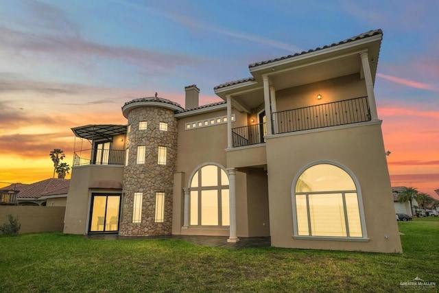 2806 S Woods Dr, Edinburg, TX 78542 - back of property at dusk featuring a balcony, a lawn, and stucco siding