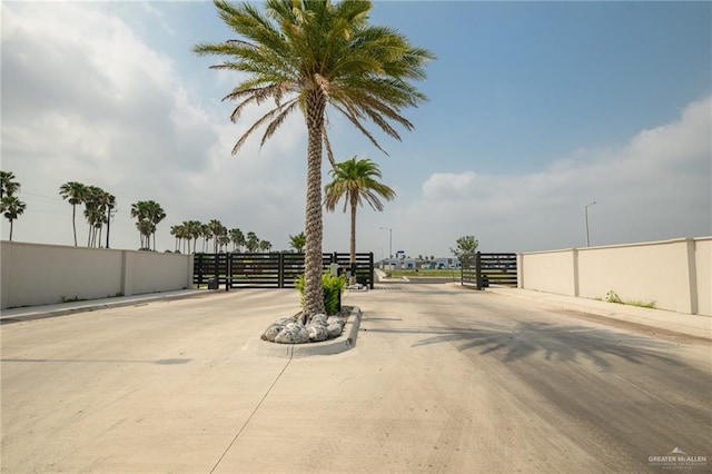 613 Cove Ln Unit 2, Weslaco, TX 78596 - view of concrete road featuring curbs, a gated entry, street lighting, and sidewalks