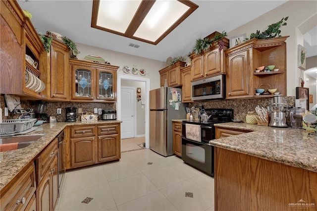 kitchen featuring brown cabinets, appliances with stainless steel finishes, and light stone countertops