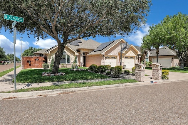 view of front of house with a front lawn, solar panels, driveway, a garage, and brick siding
