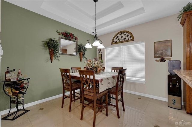 dining room with a raised ceiling, baseboards, and light tile patterned floors