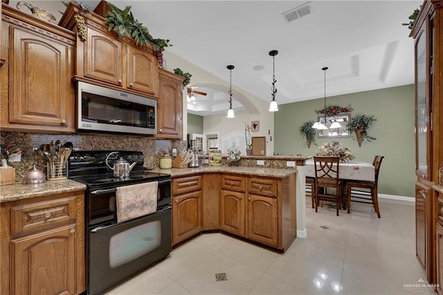 kitchen featuring stainless steel microwave, visible vents, decorative backsplash, range with two ovens, and a raised ceiling