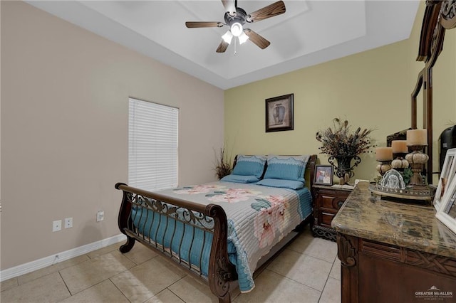 bedroom with ceiling fan, baseboards, a tray ceiling, and light tile patterned floors