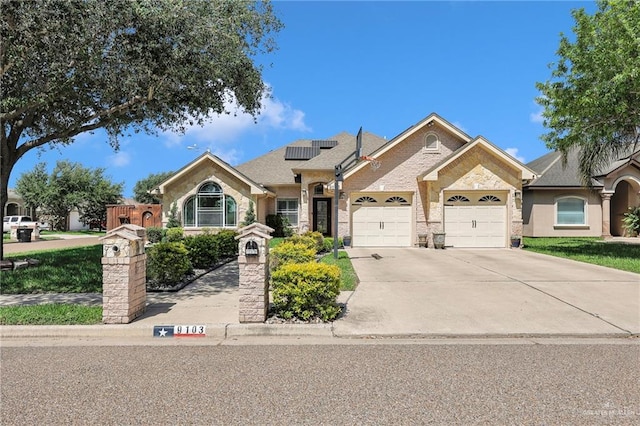 view of front facade with solar panels, driveway, and a garage