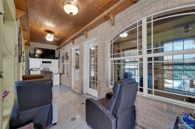 interior space with wooden ceiling, tile patterned flooring, and brick wall