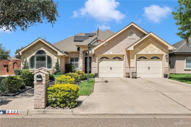 view of front facade with concrete driveway, an attached garage, solar panels, and brick siding