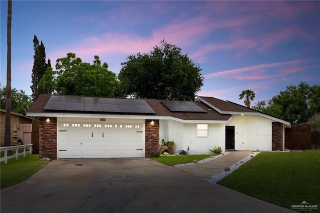 view of front of house featuring a yard, fence, driveway, and roof mounted solar panels