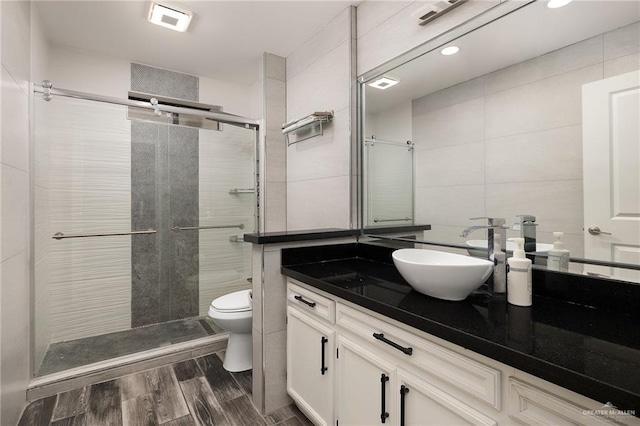 bathroom featuring a stall shower, wood finished floors, toilet, and tile walls