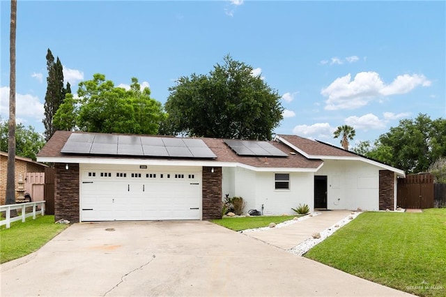 view of front facade with fence, concrete driveway, solar panels, and a front lawn