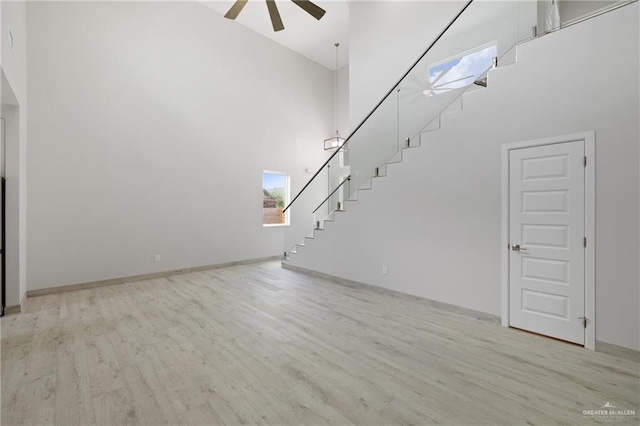 1220 N Lincoln Ave, San Juan, TX 78589 - unfurnished living room featuring a high ceiling, stairs, a ceiling fan, wood finished floors, and baseboards