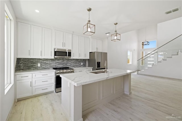 1220 N Lincoln Ave, San Juan, TX 78589 - kitchen with stainless steel appliances, a sink, tasteful backsplash, light wood finished floors, and a kitchen island with sink