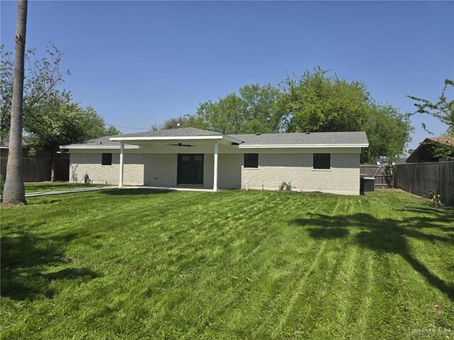 rear view of property featuring cooling unit, a patio, and a lawn