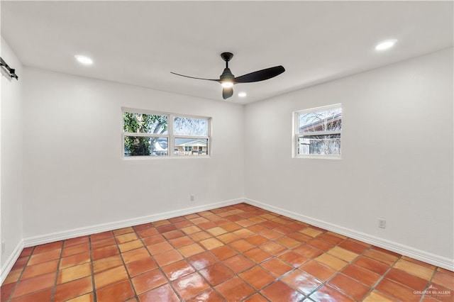 empty room featuring a barn door and ceiling fan