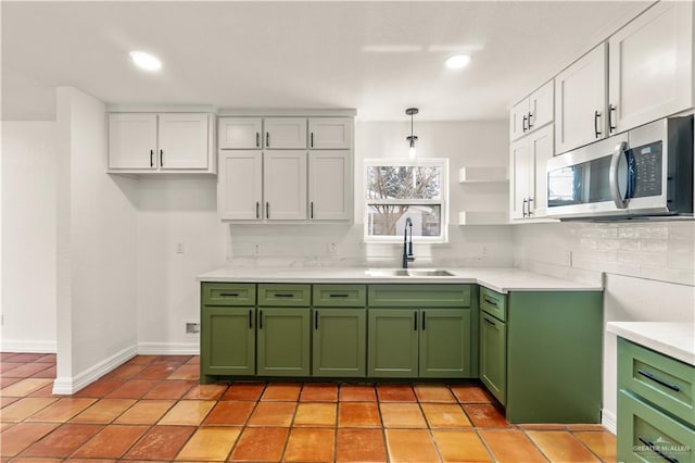 kitchen with sink, hanging light fixtures, white cabinets, green cabinetry, and decorative backsplash