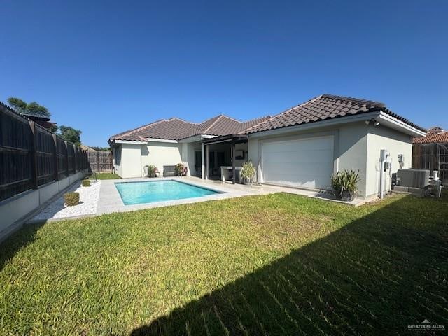 back of house with a lawn, a garage, and a fenced in pool