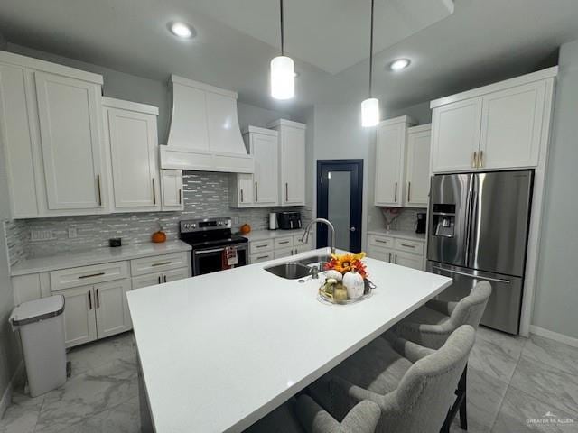 kitchen with custom exhaust hood, a kitchen island with sink, sink, appliances with stainless steel finishes, and tasteful backsplash