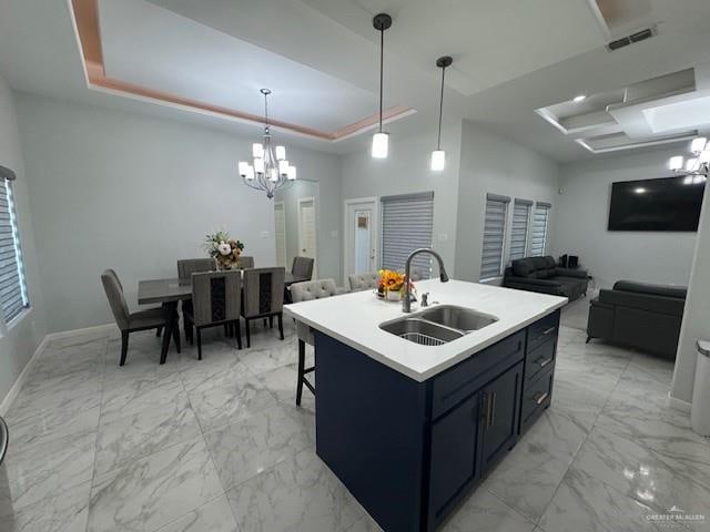 kitchen with pendant lighting, an island with sink, a tray ceiling, and sink