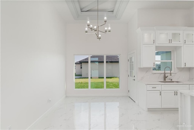 interior space with a sink, a chandelier, marble finish floor, baseboards, and a wealth of natural light