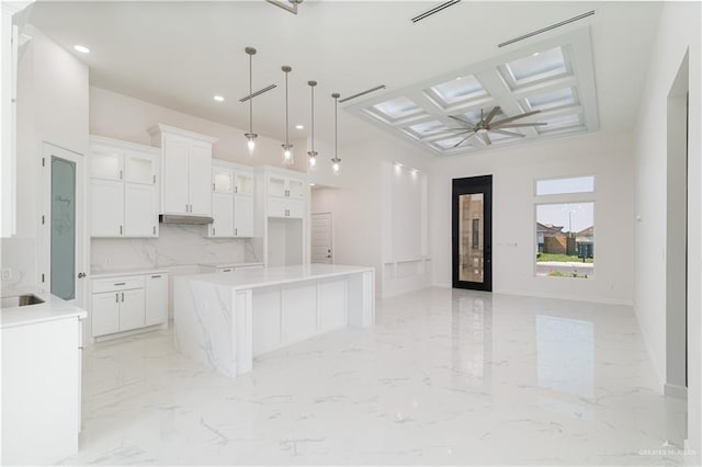 kitchen with open floor plan, coffered ceiling, marble finish floor, and under cabinet range hood