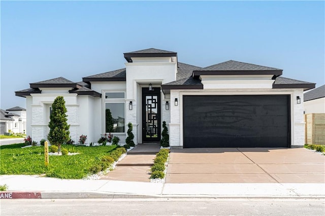prairie-style home featuring a shingled roof, an attached garage, concrete driveway, and stucco siding