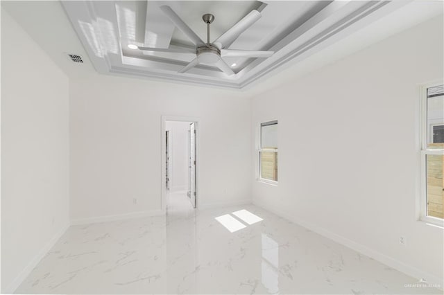 empty room featuring ceiling fan, a tray ceiling, marble finish floor, and visible vents