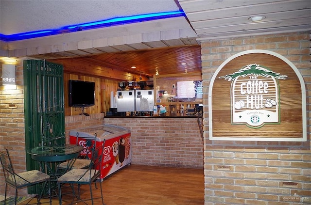 bar featuring wood ceiling, wood-type flooring, and brick wall