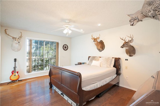 bedroom featuring ceiling fan, a textured ceiling, baseboards, and wood finished floors