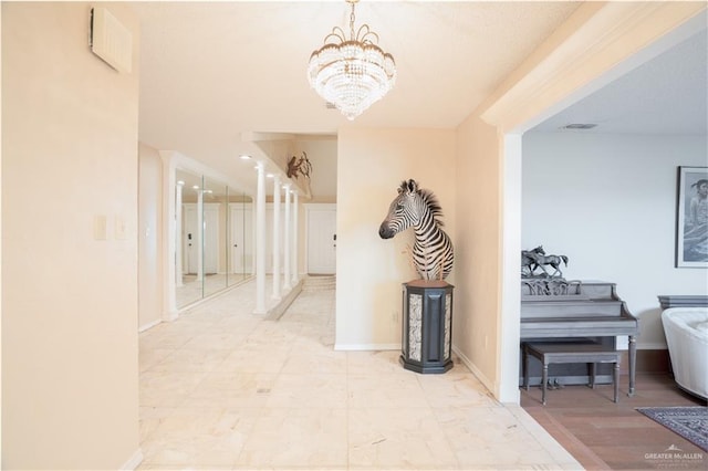 hall with a notable chandelier, visible vents, and baseboards