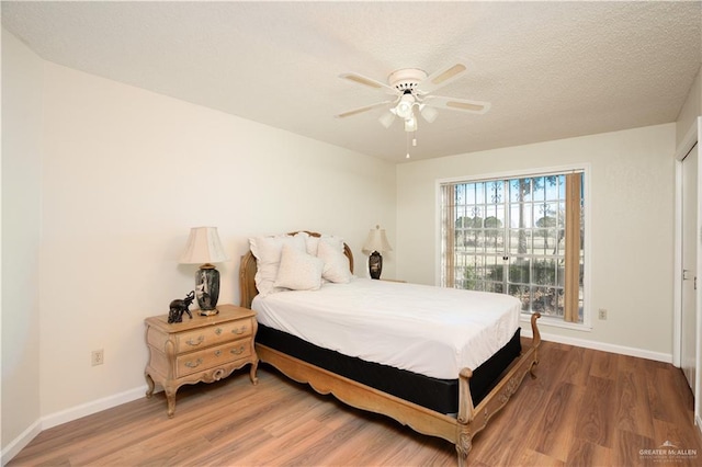 bedroom featuring a textured ceiling, wood finished floors, and baseboards