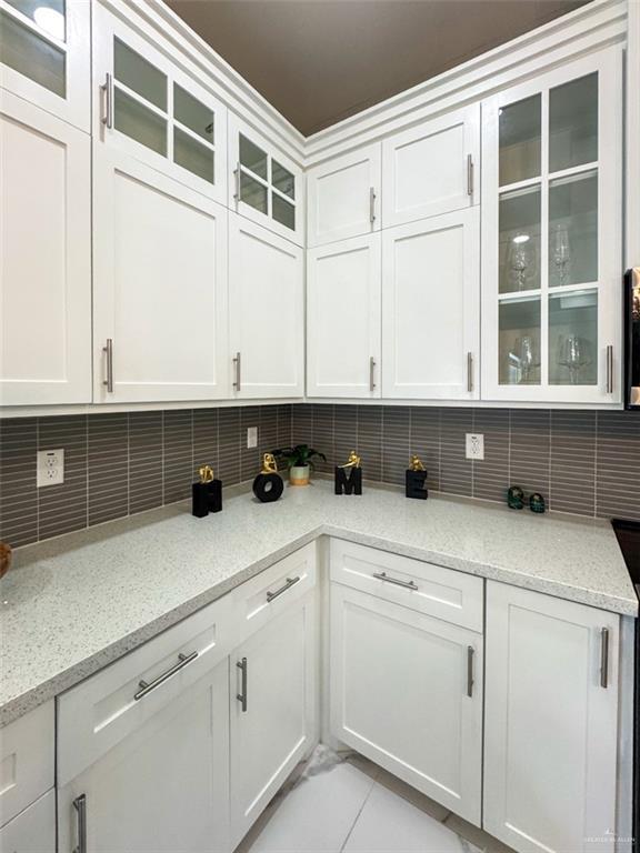 1313 W Dawes Ave W, Alton, TX 78573 - kitchen with backsplash, white cabinetry, glass insert cabinets, and light stone counters