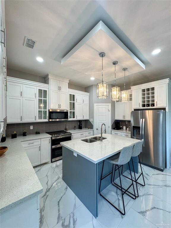 1313 W Dawes Ave W, Alton, TX 78573 - kitchen featuring stainless steel appliances, a sink, a kitchen breakfast bar, a chandelier, and light marble finish floors